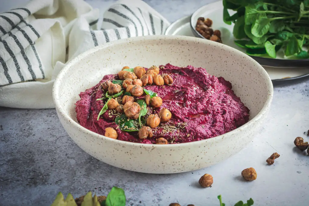 Beet hummus in bowl, topped with crispy chickpeas