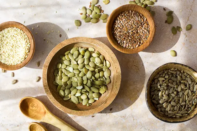 sesame seeds, flax seeds, pumpkin seeds and sunflower seeds in small wooden bowls