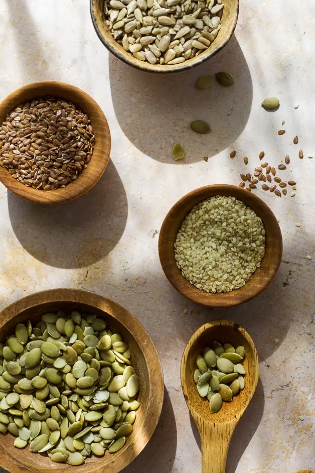 sesame seeds, flax seeds, pumpkin seeds and sunflower seeds in small wooden bowls