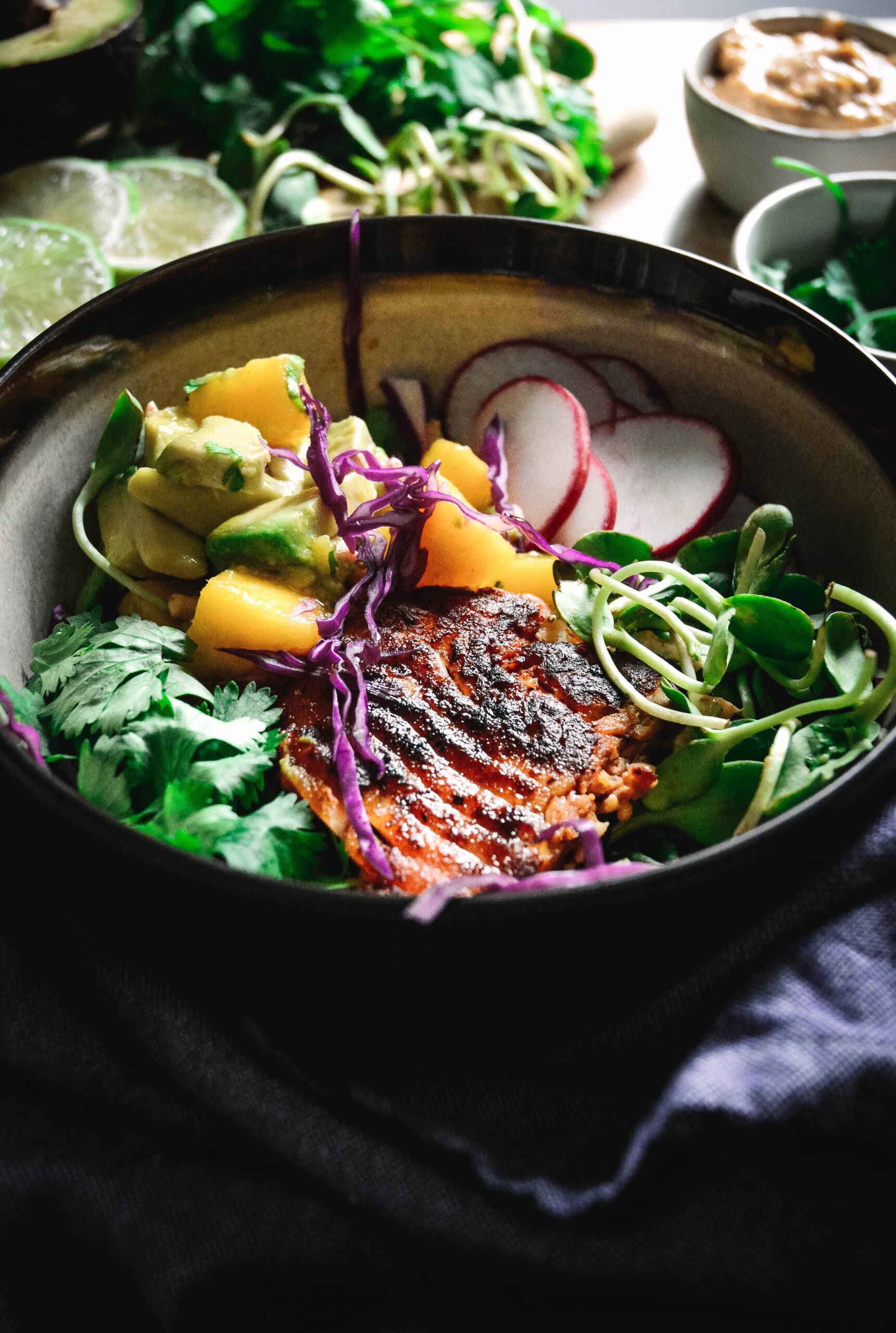 grilled fish, avocado, radish slices, cilantro and sprouts in a bowl