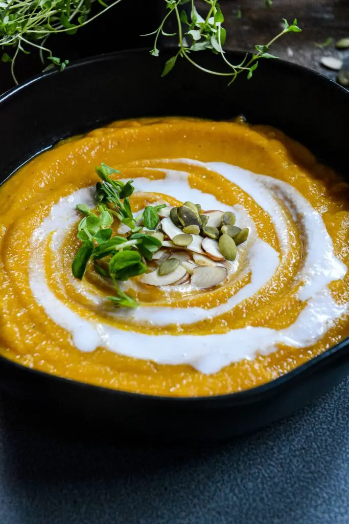 Squash soup up close with coconut cream swirl and pumpkin and almonds 