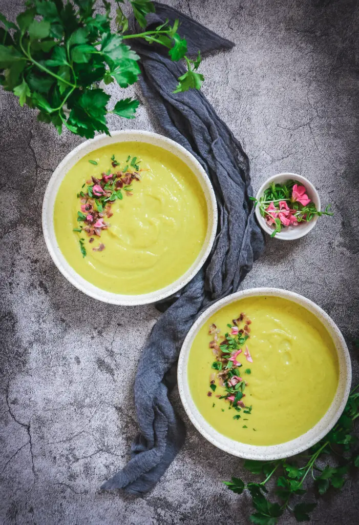 2 bowls of golden cauliflower soup on table with napkin 