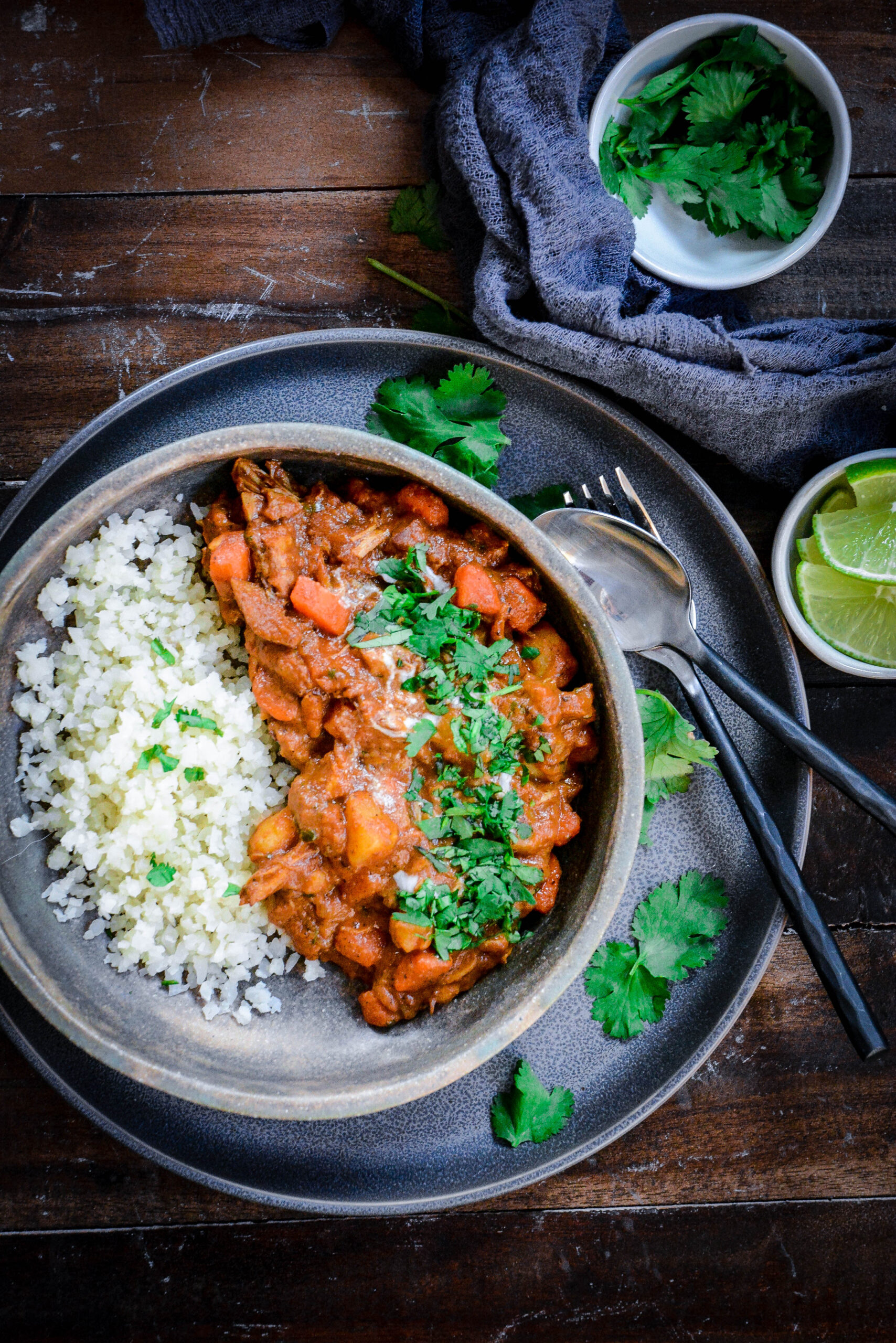 chicken masala on a plate with rice and herbs on top