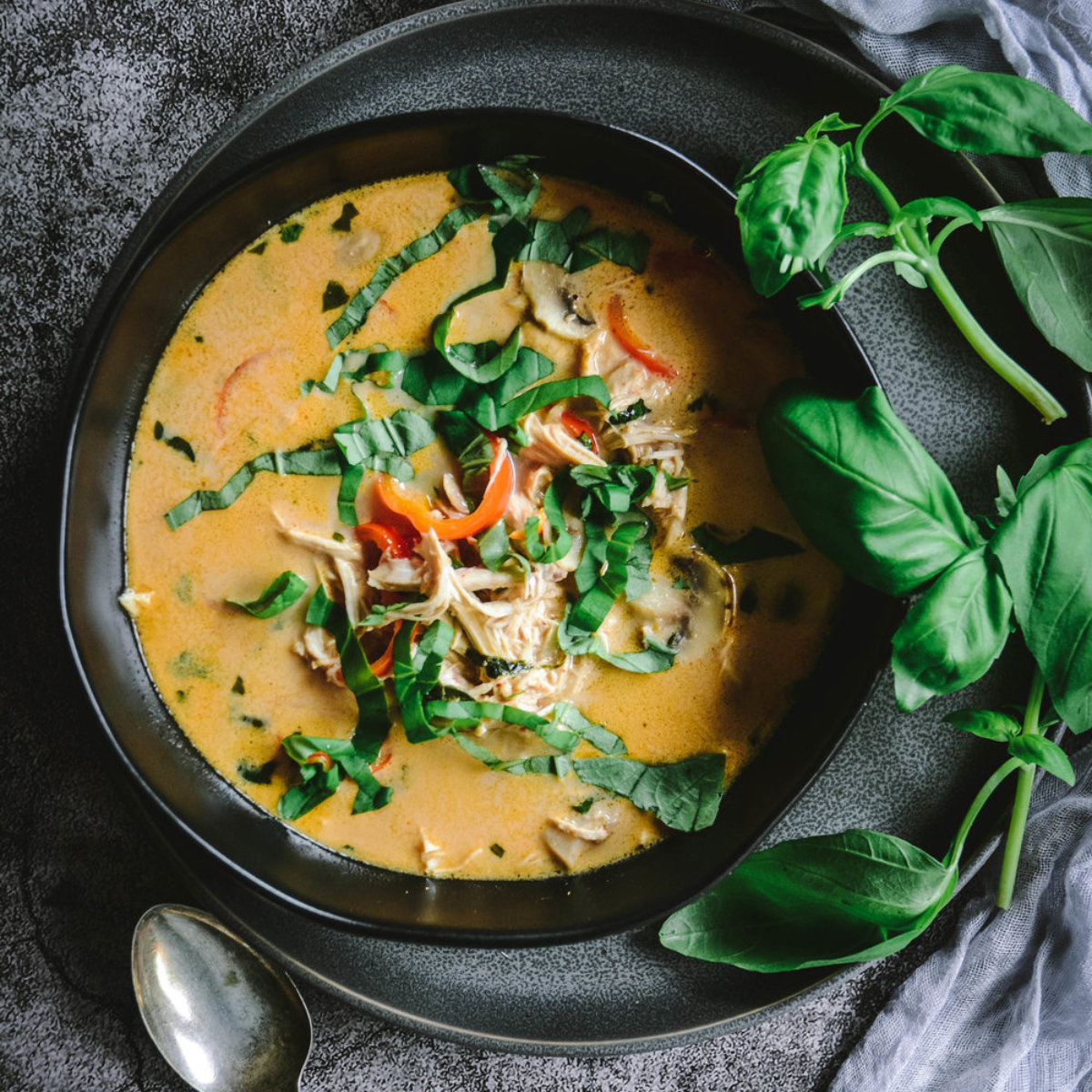 Low-Carb Thai Coconut Chicken Soup with Lemongrass in bowl with spoons and chopped basil