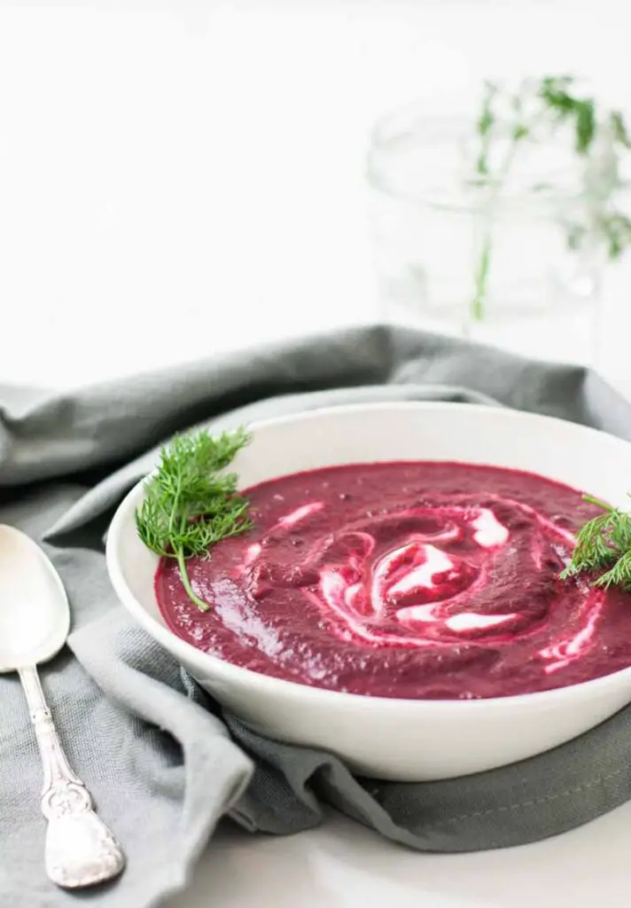 Roasted beet soup in bowl with napkin and spoon