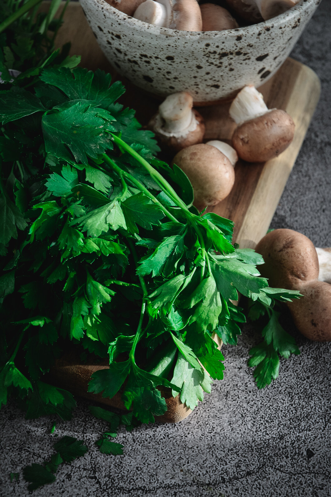 Mushrooms in bowl with parsley on cutting board