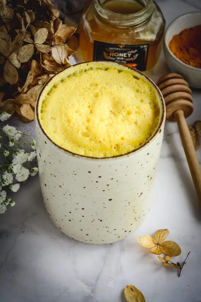 turmeric milk in mug, honey, dry flower