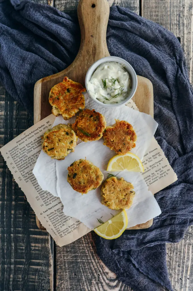 tuna and chickpea bites on cutting board and parchment paper with lemon slices and lemon dill mayo