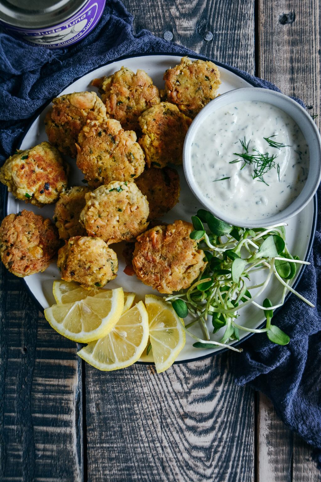 tuna and chickpea bites on plate with greens, lemon slices and lemon dill mayo. 