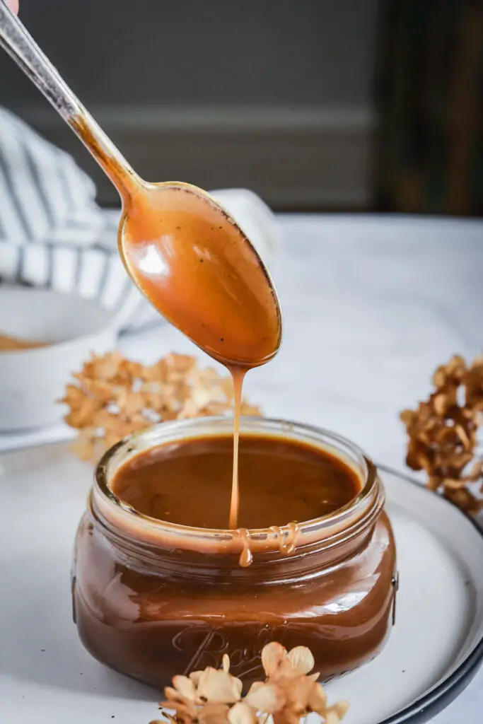 salted caramel sauce dripping from spoon into jar