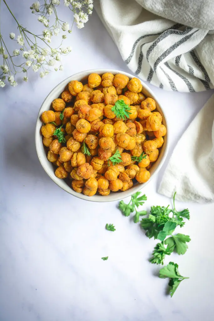 Crispy roasted chickpeas in bowl with parsley and black and white napkin