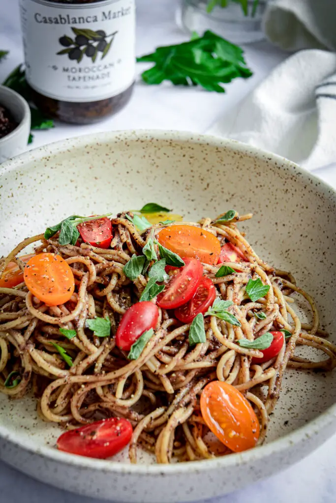 Moroccan Tapenade Spaghetti with Tomatoes and Herbs with herbs and jar of tapenade 