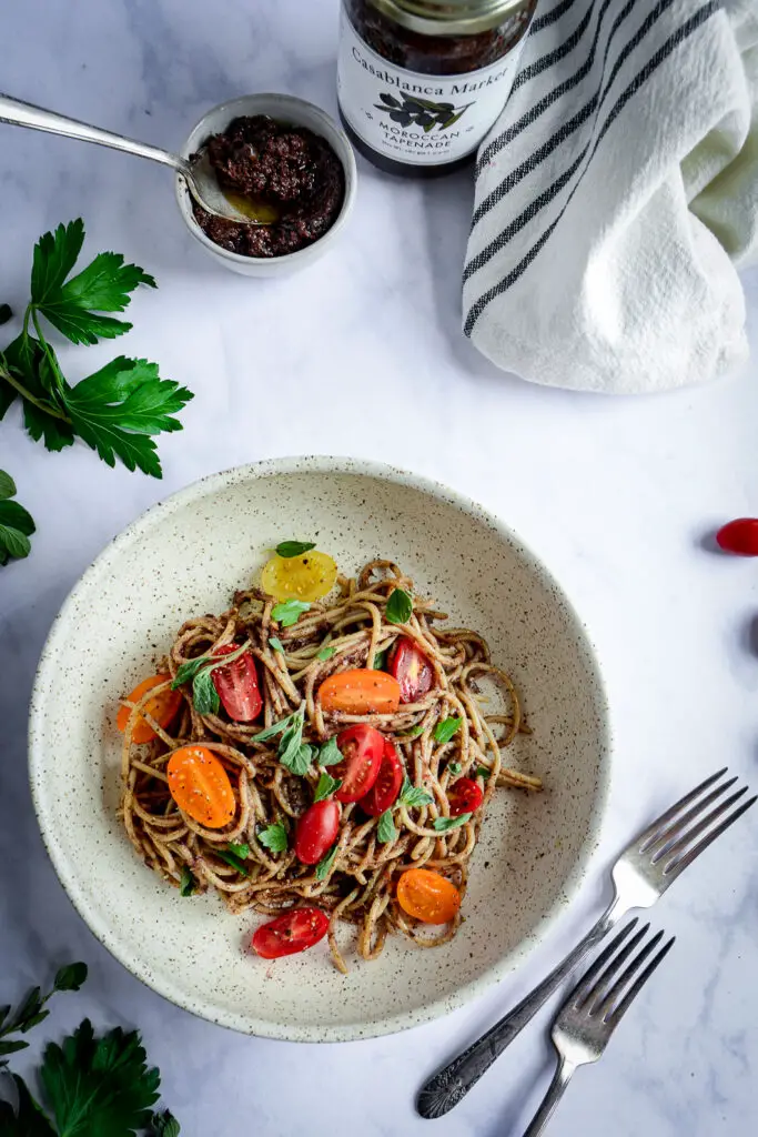 Moroccan Tapenade Spaghetti with Tomatoes and Herbs in bowl with napkin, bowl of tapenade and forks 