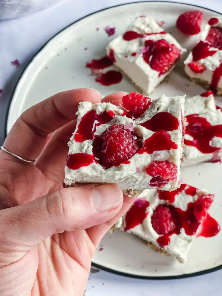 Vegan Raspberry Cheesecake Bites with Rose Cardamom Honey in hand