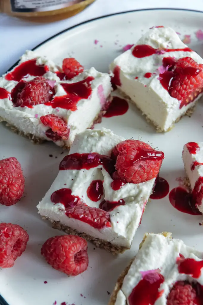 Vegan Raspberry Cheesecake Bites with Rose Cardamom Honey on plate up close. 