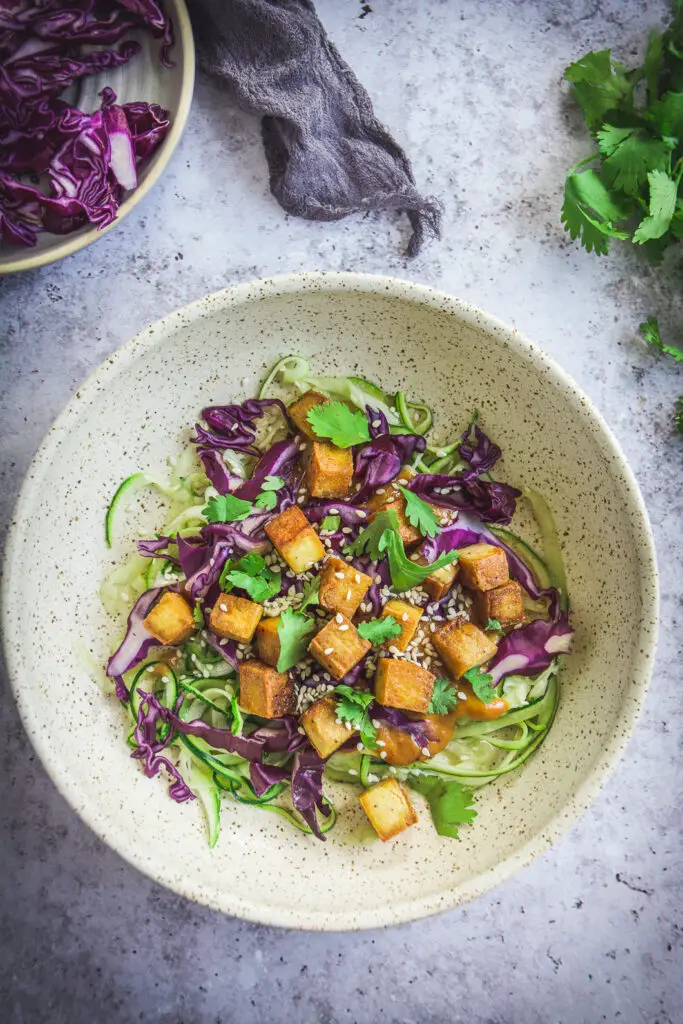 Zoodles with Thai Peanut Sauce and Tofu on plate with cilantro and red cabbage