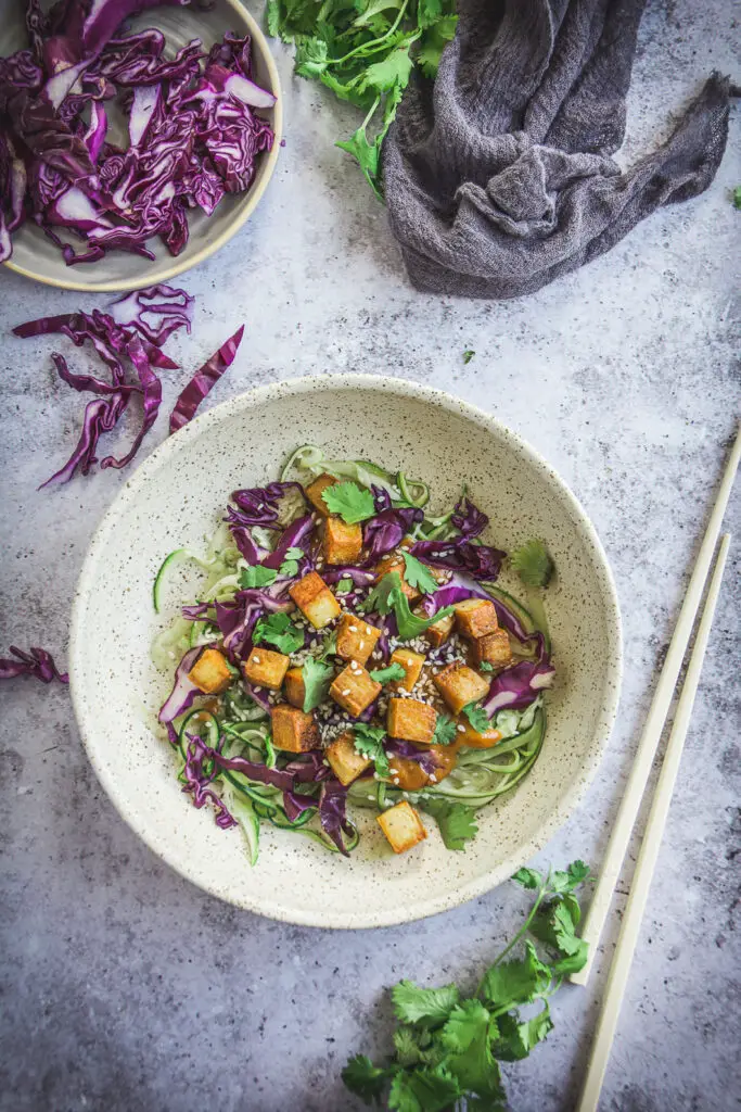 Zoodles with Thai Peanut Sauce and Tofu on table with chopsticks and cilantro 