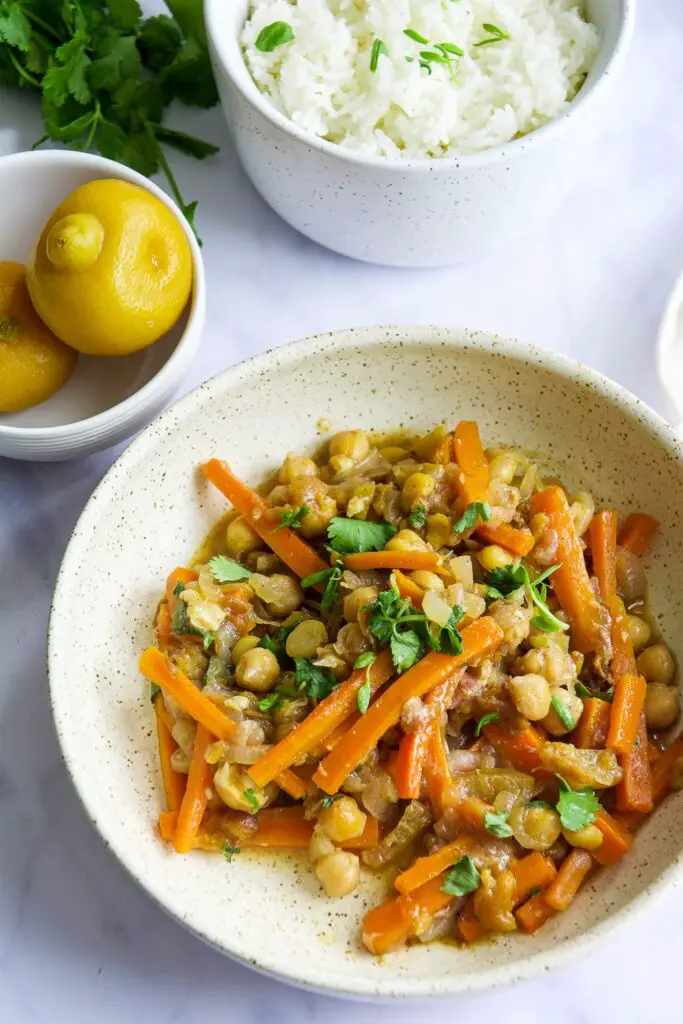 Moroccan Chickpea Tagine with Preserved Lemons in bowl with cilantro and preserved lemons in bowl in background