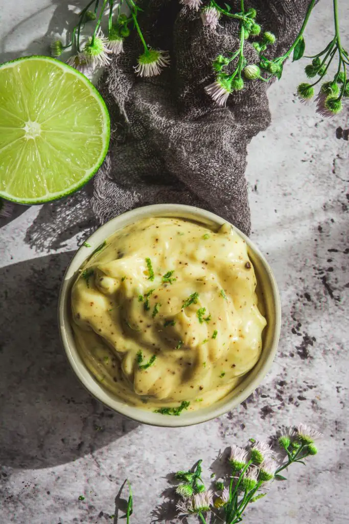 Chipotle Mayo on table with lime and green, yellow flowers and grey napkin