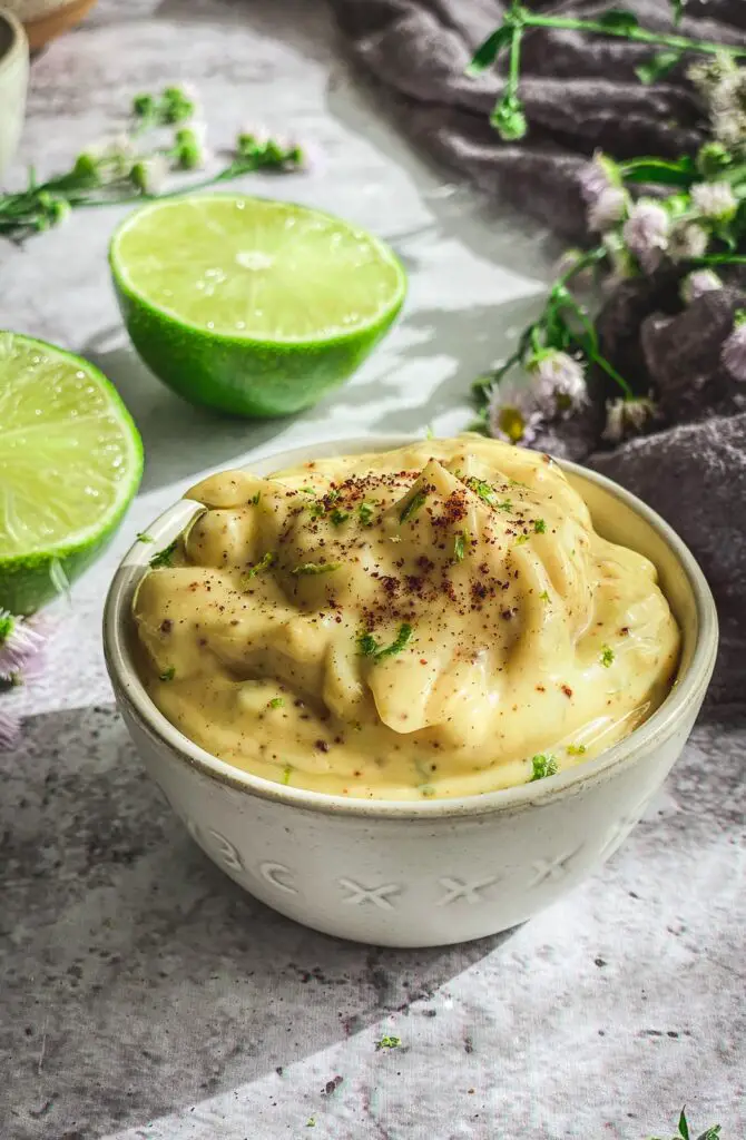 Chipotle Mayo in bowl on table with lime halves and grey napkin