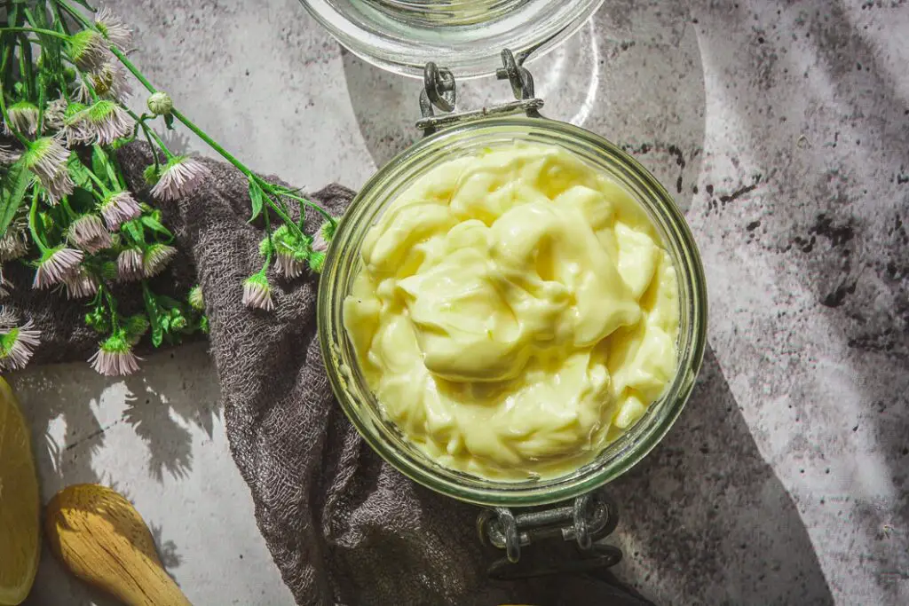 Paleo Mayo on table in har with flowers and dark grey napkin