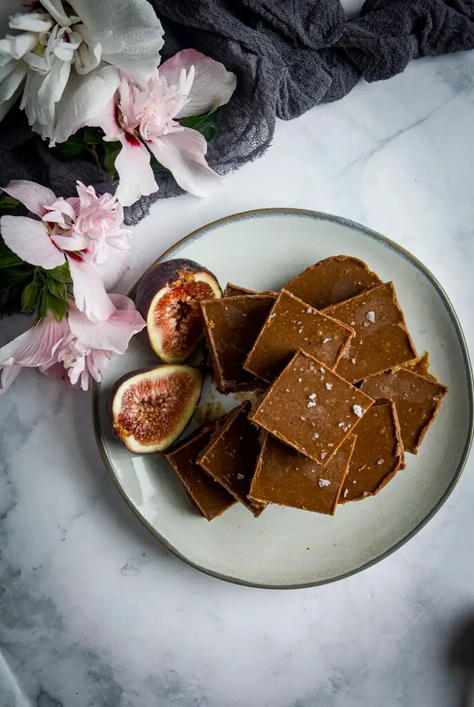 Vegan chocolate fudge on plate with fig halves and hibiscus flowers