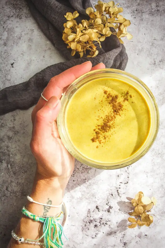 pumpkin spice latte in clear mug held by hand