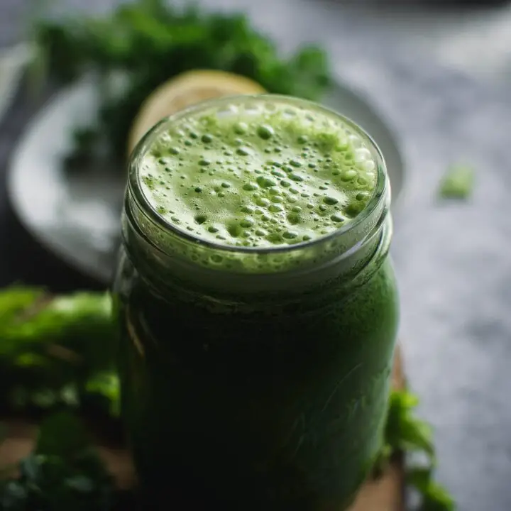 Super Green Parsley and Cilantro Smoothie with straw in glass mug
