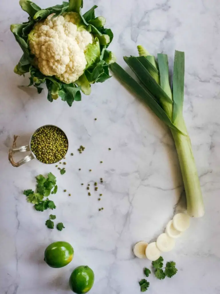 Cauliflower, lime, cilantro, mung bean curry and leek on table