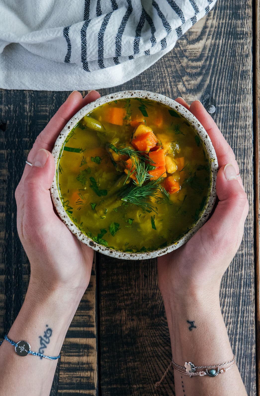 Bone Broth Vegetable Soup in bowl hands in hands