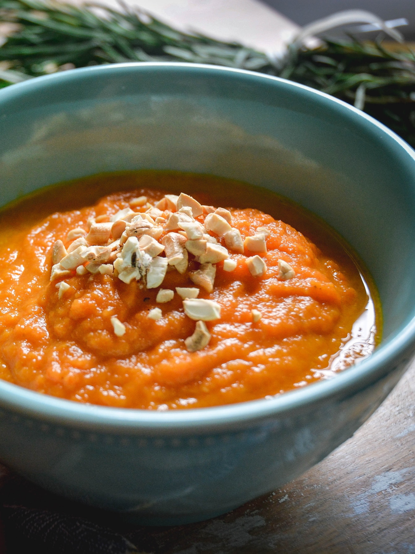carrot soup in blue bowl topped with cashews