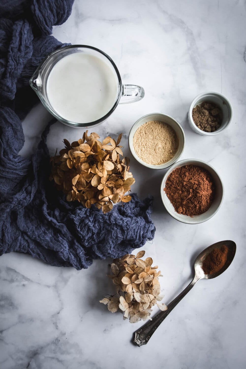 dried hydrangea, maca in bowl, cacao in bowl, almond milk in mug, cinnamon in bowl and napkin