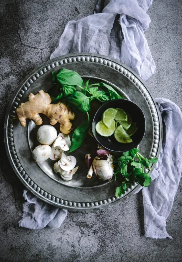 mushrooms, basil, cilantro, ginger, lime slices and garlic on platter