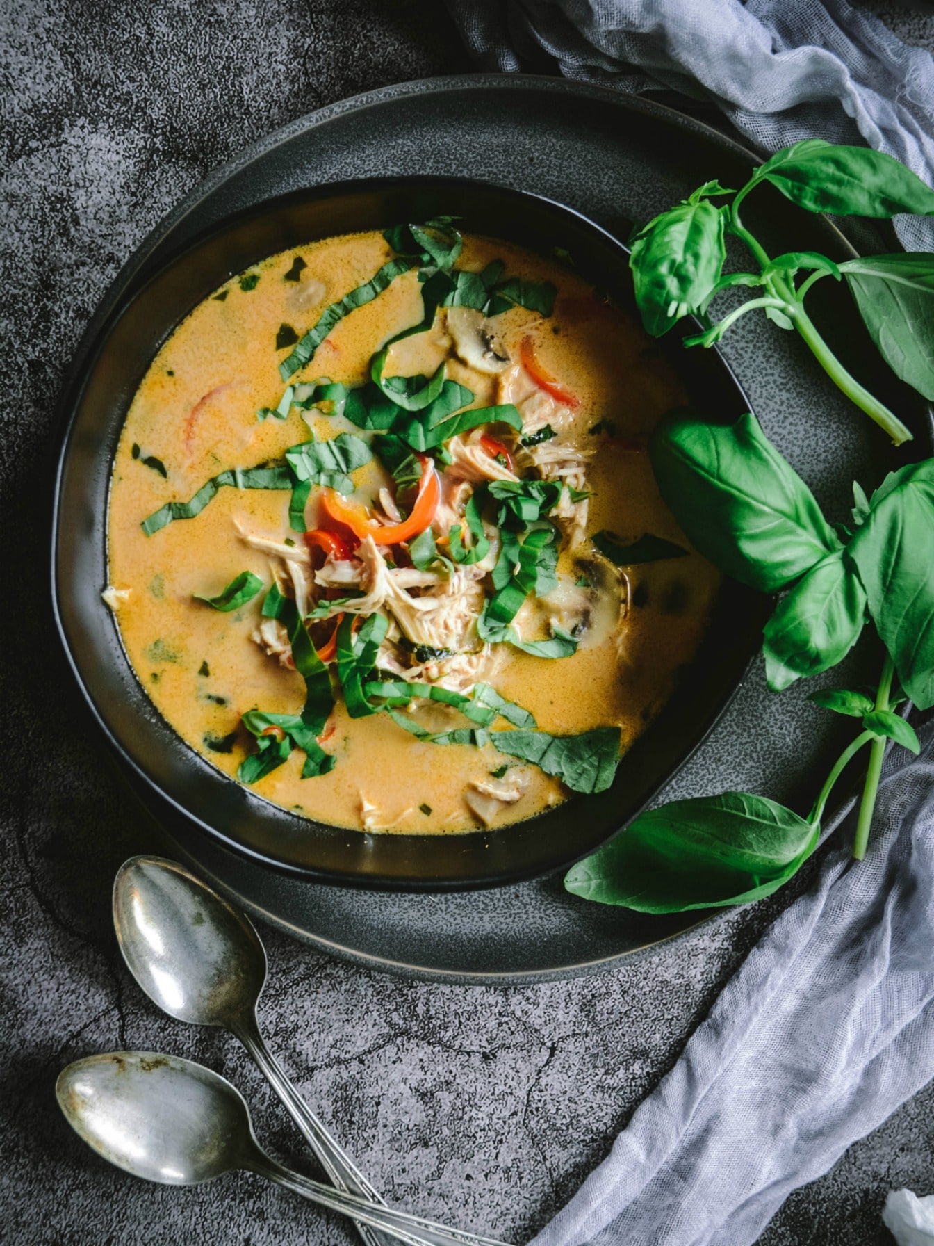 Low-Carb Thai Coconut Chicken Soup with Lemongrass in bowl with spoons and chopped basil