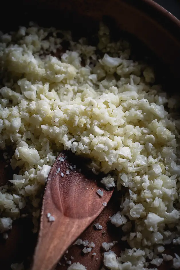 cooked cauliflower rice in pan with wooden spoon