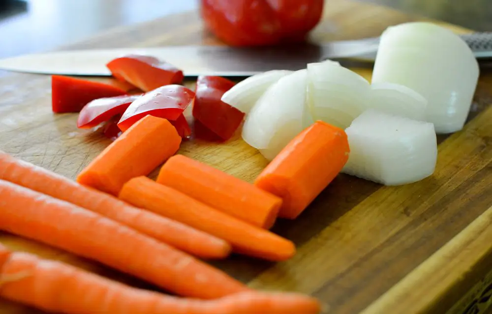 carrots onions and peppers cut up on cutting board
