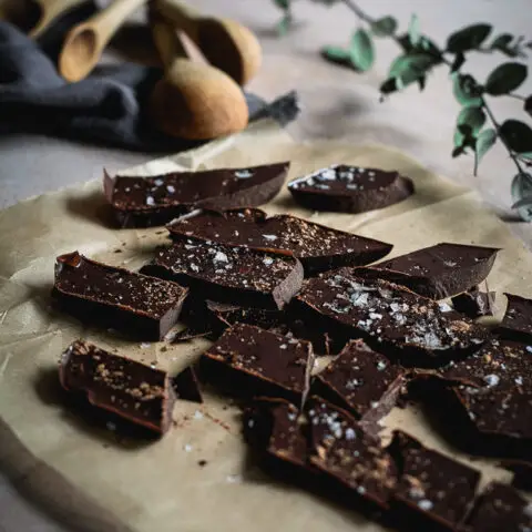 chocolate chunks on parchment paper with wooden spoons and a green branch