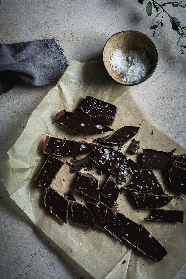chocolate chunks on parchment paper with a bowl of salt