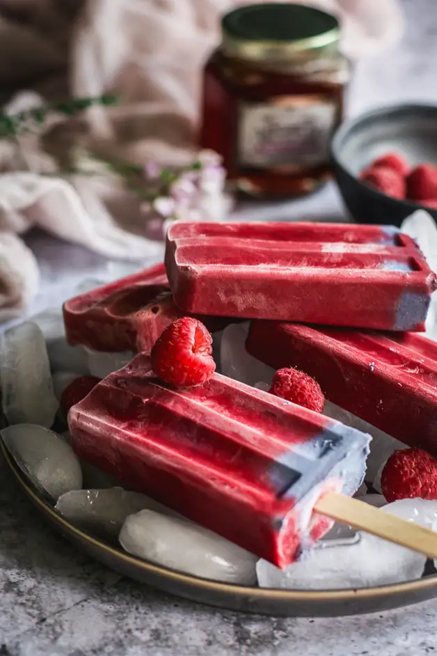 raspberry popsicles on a plate of ice cubes