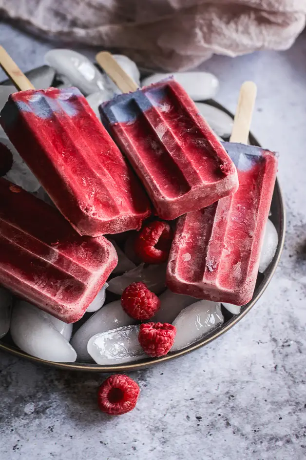 raspberry popsicles on a plate of ice cubes
