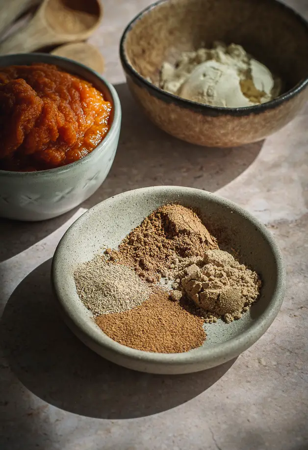 little bowl of spices, small bowl of pumpkin puree, and a bowl of pea protein powder