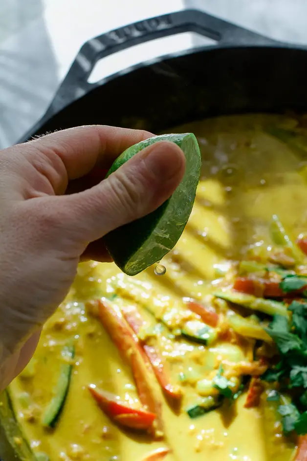 vegetables in a peanut sauce hand squeezing lime