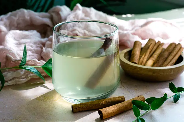 glass of water with apple cider vinegar and cinnamon, cinnamon sticks on table