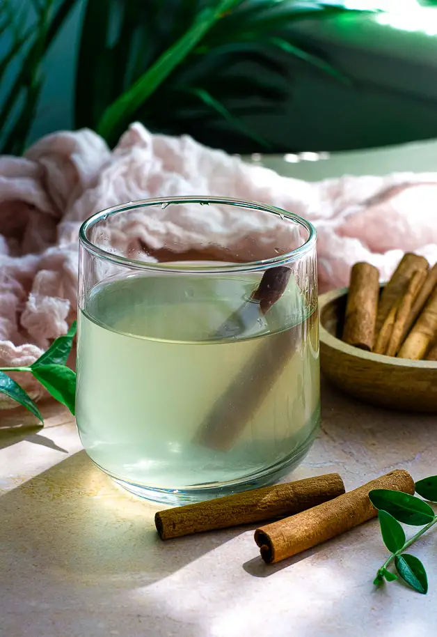 glass of water with apple cider vinegar and cinnamon, cinnamon sticks on table