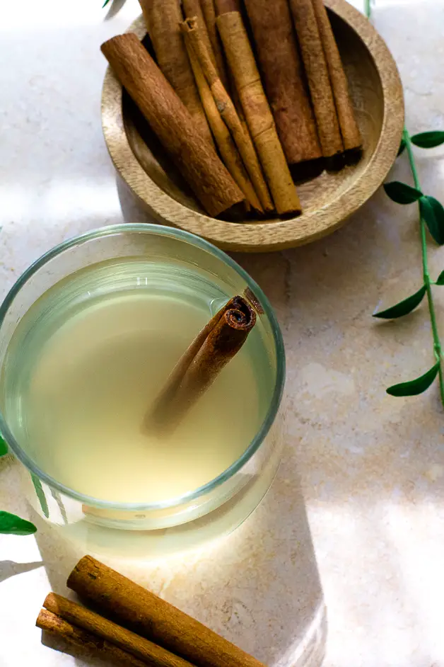 glass of water with apple cider vinegar and cinnamon, cinnamon sticks on table