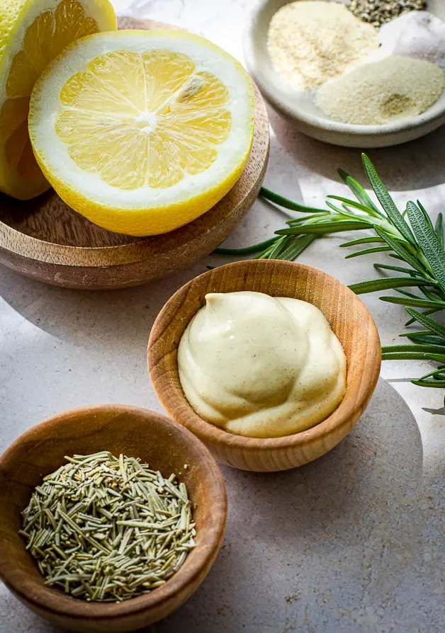 small wood bowls with mustard, lemon halves and dried rosemary