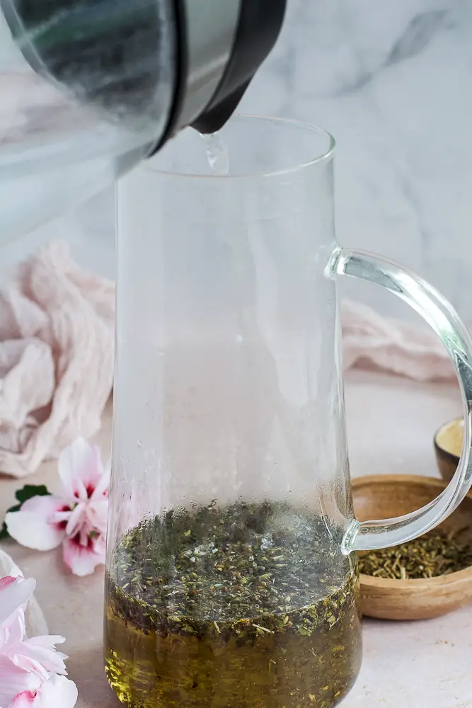 herbs and water being poured into a carafe