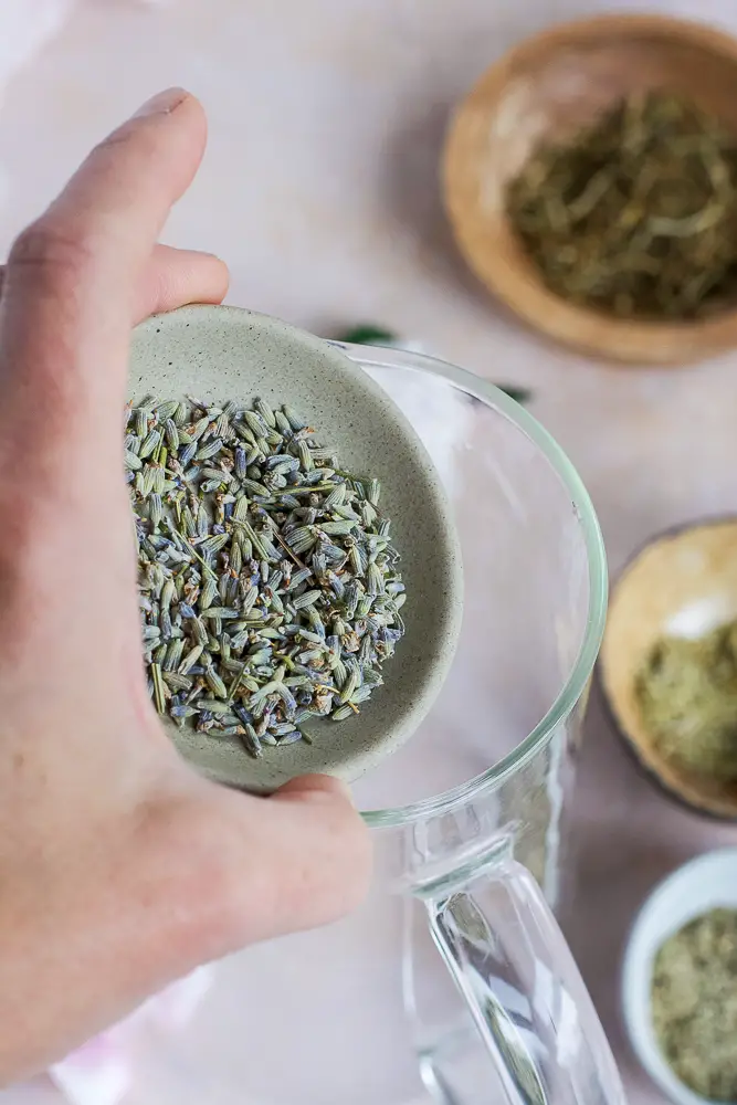 herbs in a bowl being poured into a glass carafe