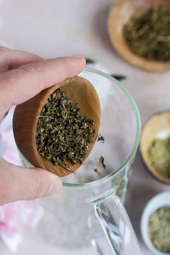 herbs in a bowl being poured into a glass carafe