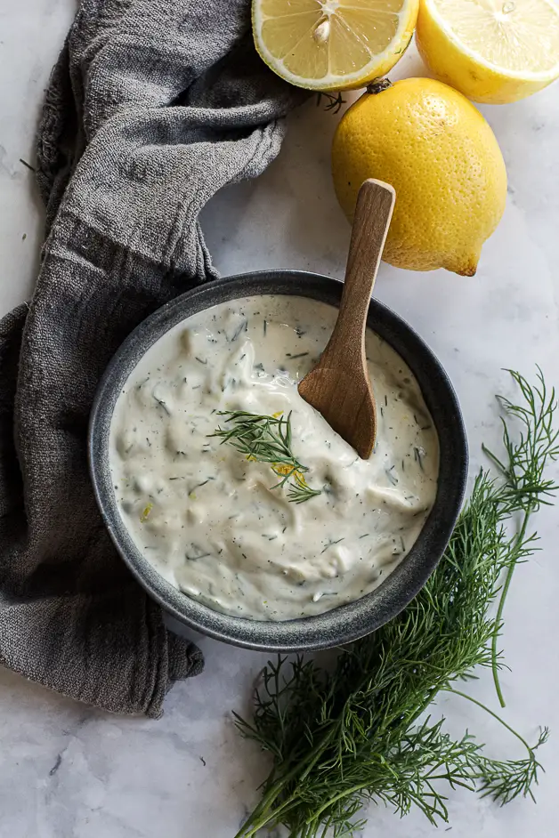 mixed mayo sauce in a bowl with dill and lemons